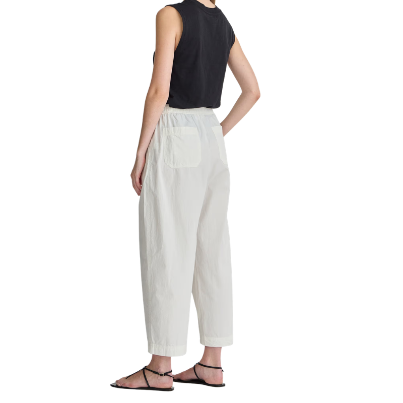 Person wearing a black sleeveless top and white pants on a white background