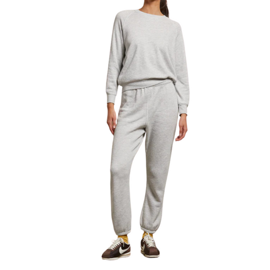 Person wearing a gray sweatshirt and pants set on a white background