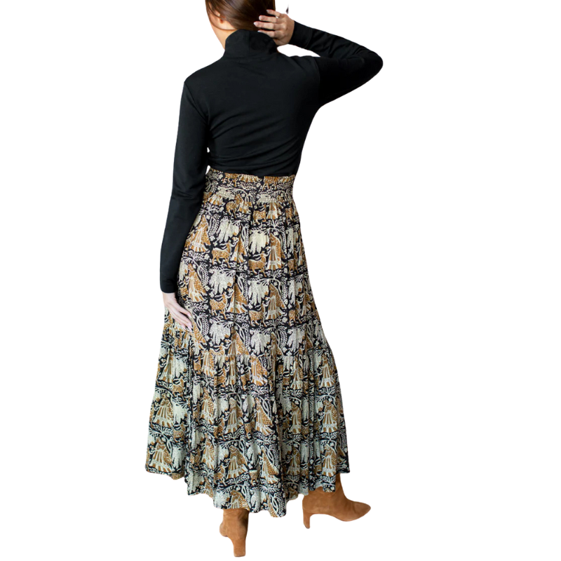 Person wearing a long, patterned skirt with a plain background