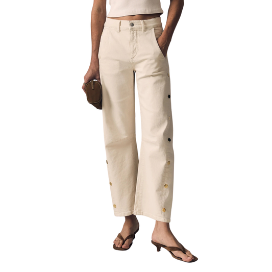 Person wearing beige pants with button details on a white background