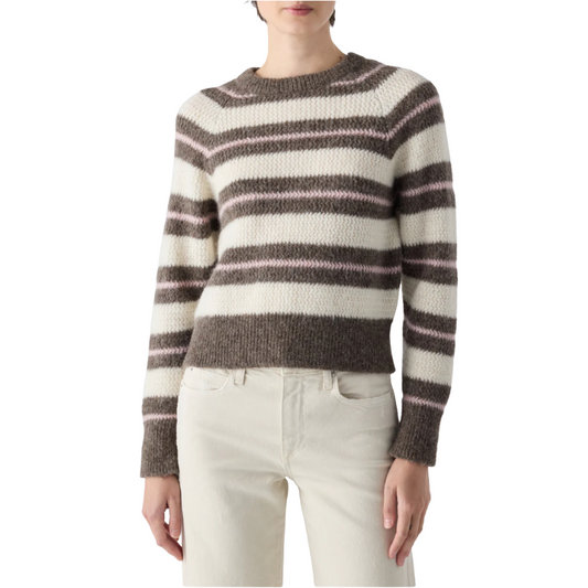 Person wearing a striped sweater and white pants on a white background