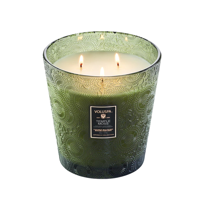 Green candle with intricate design and 'Voluspa' label on a white background
