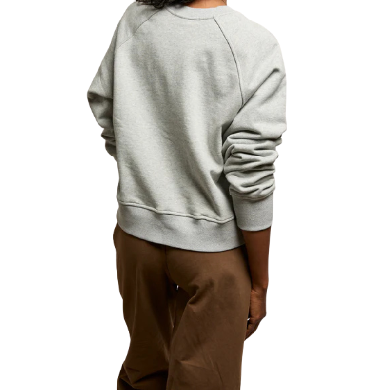 Person wearing a light gray sweatshirt and brown pants on a white background