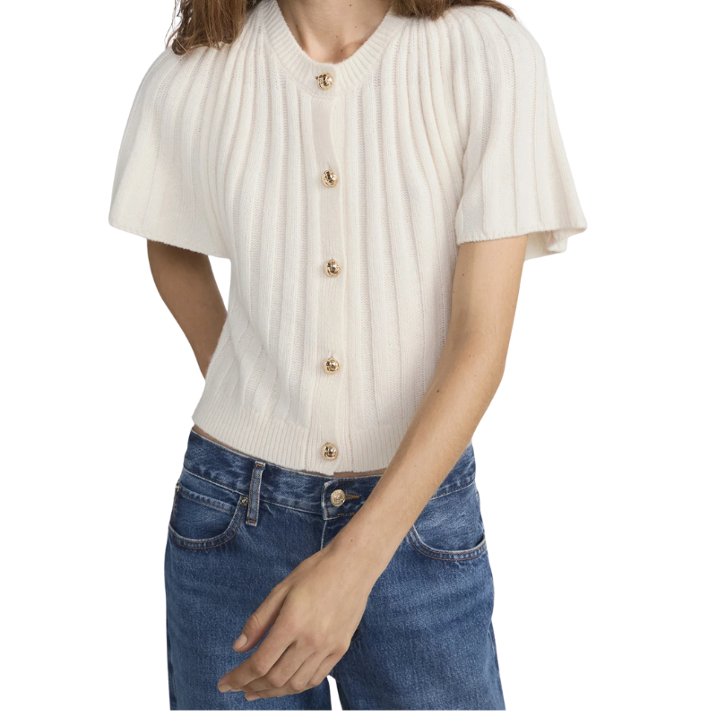 Person wearing a cream ribbed knit cardigan with gold buttons and blue jeans on a white background