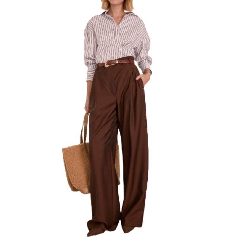 Person wearing a striped shirt and brown wide-leg pants holding a straw bag on a white background