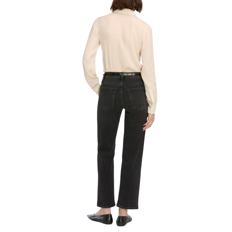 Person wearing a beige shirt and black jeans on a white background