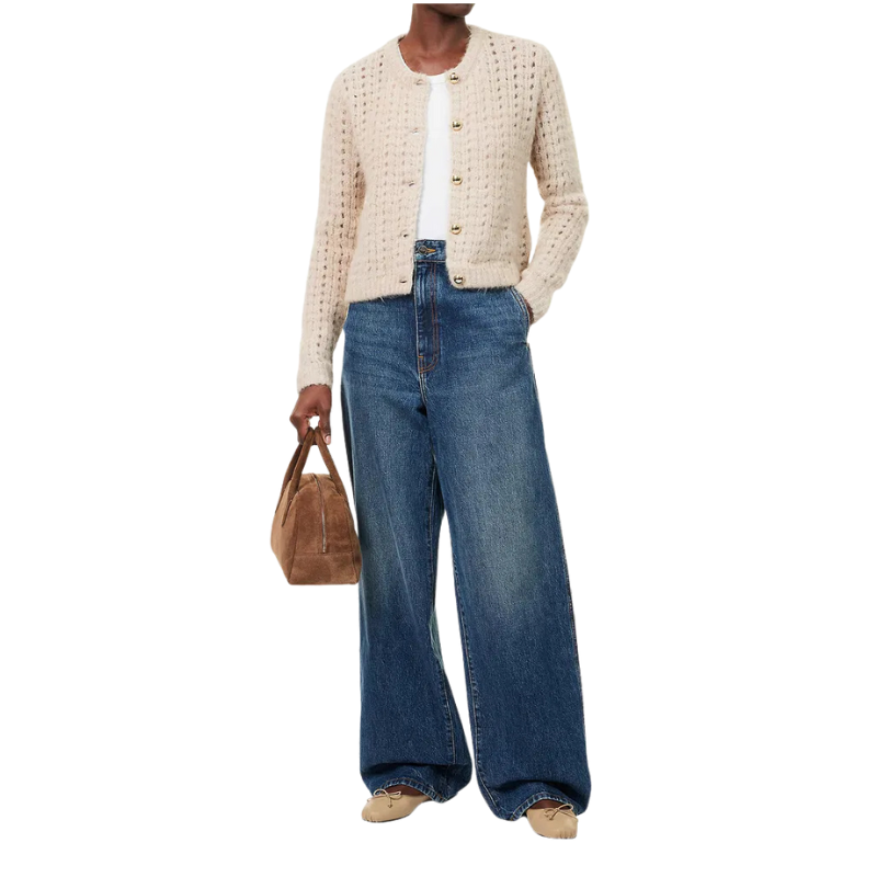 Person wearing a beige cardigan, white shirt, blue jeans, and holding a brown bag on a white background