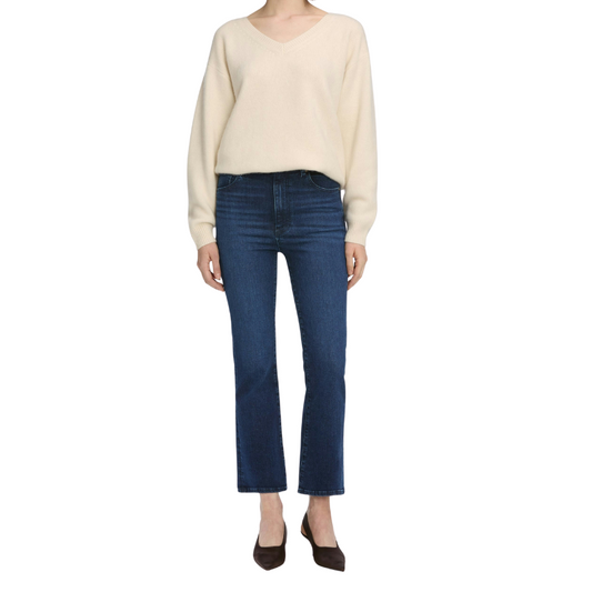 Person wearing a beige sweater and blue jeans on a white background