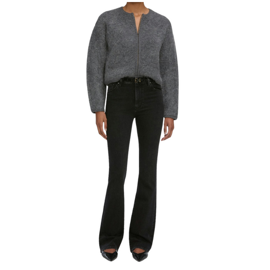 Person wearing a gray zip-up sweater and black flared jeans on a white background