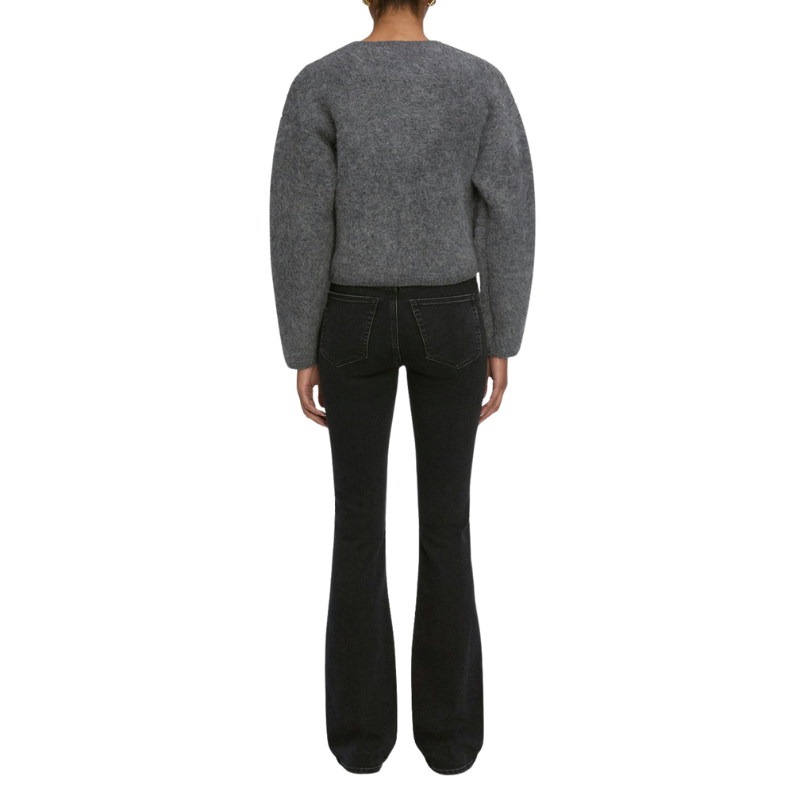 Person wearing a gray sweater and black pants on a white background
