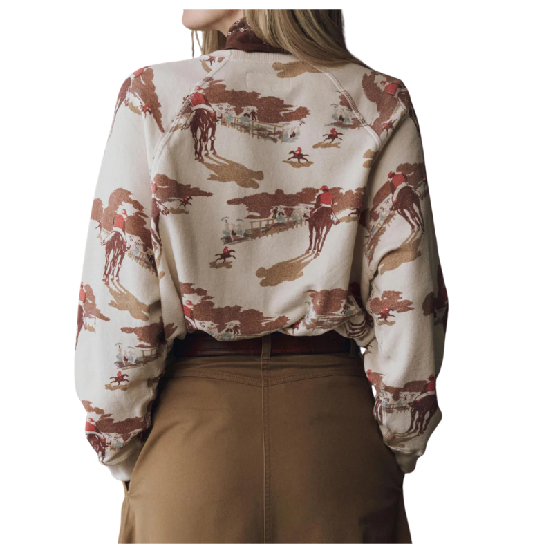Person wearing a patterned blouse with horse and rider design on a white background