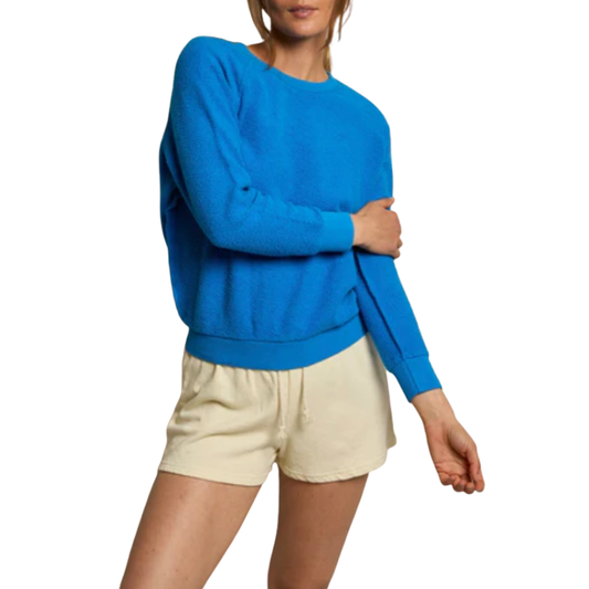 Person wearing a blue sweatshirt and beige shorts on a white background