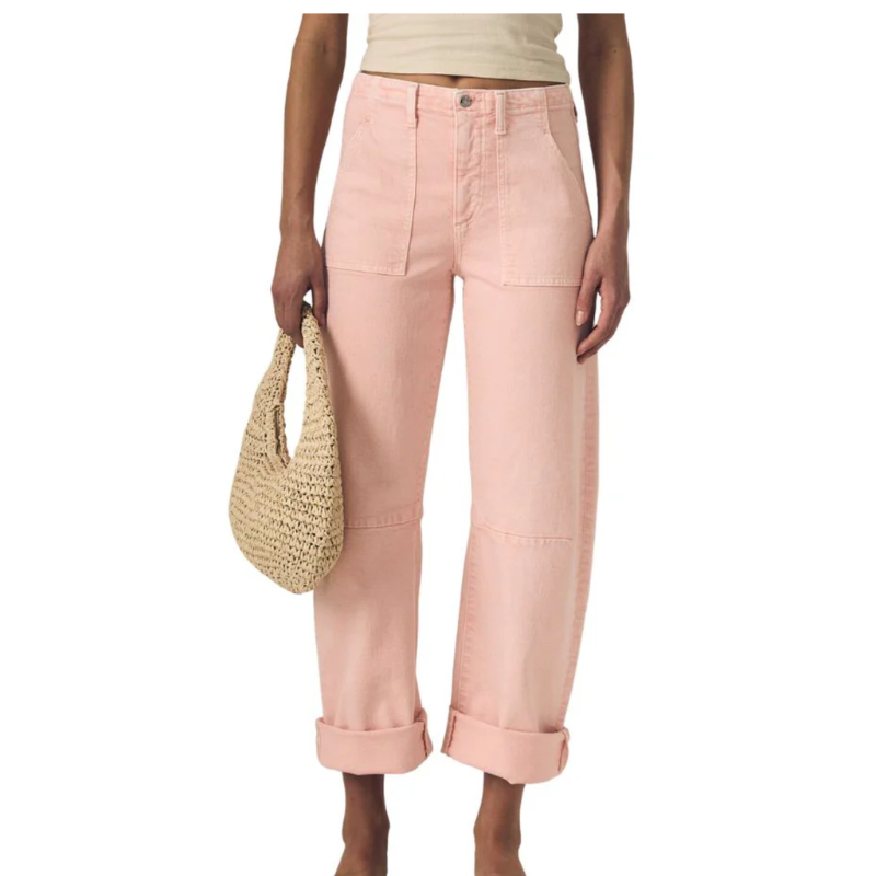Person wearing light pink pants holding a straw bag on a white background