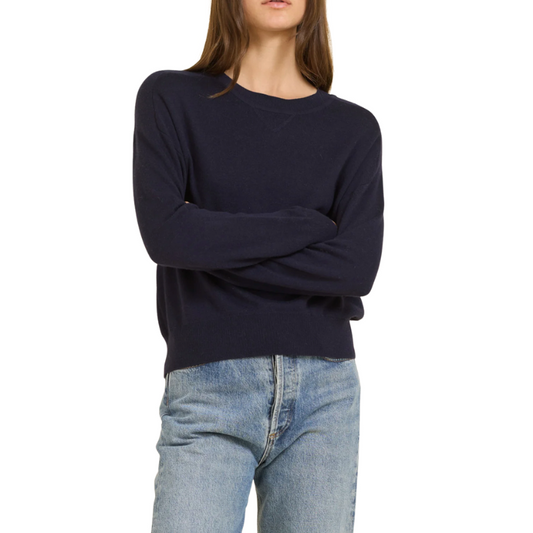 Person wearing a navy sweater and light blue jeans on a white background