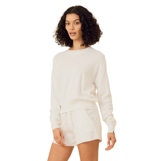 Woman wearing a white sweater and shorts set on a white background