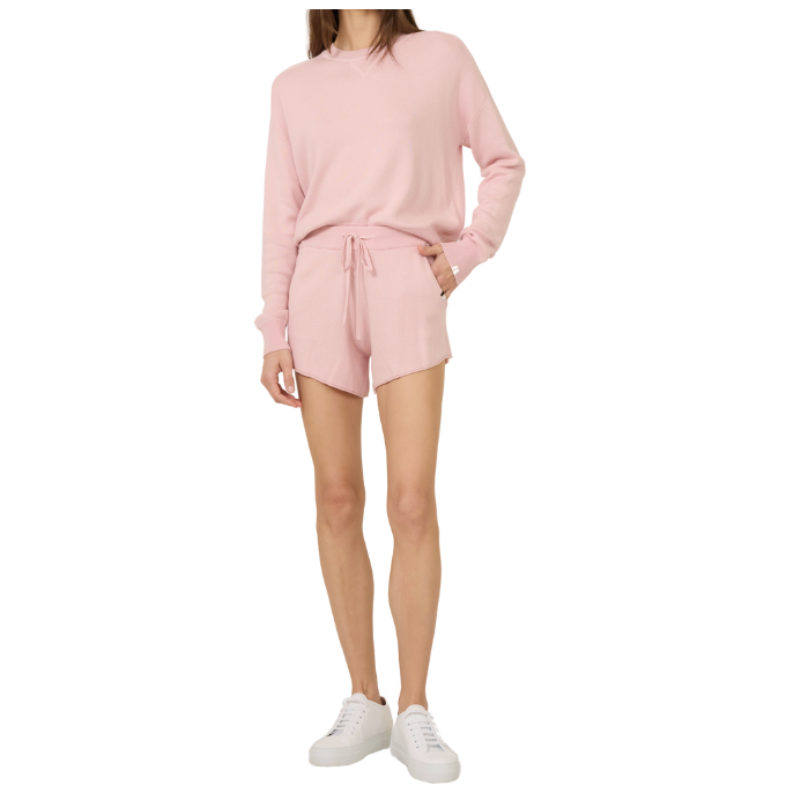 Person wearing a pink outfit with shorts and a long-sleeve top on a white background