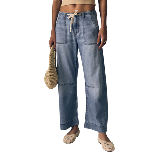 Person wearing light blue denim pants on a white background
