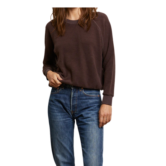 Person wearing a brown sweater and blue jeans on a white background