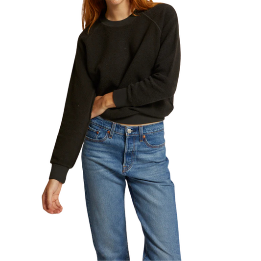 Person wearing a black sweatshirt and blue jeans on a white background