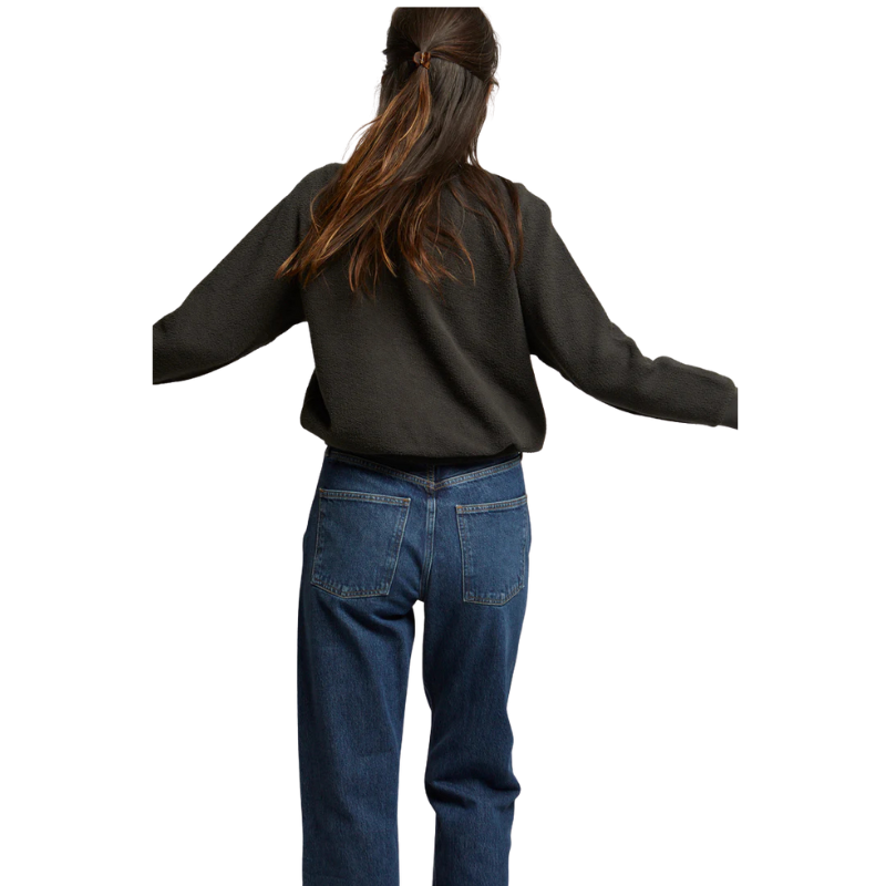 Person wearing a black sweater and blue jeans on a white background