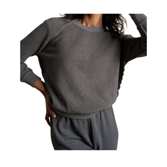 Person wearing a gray sweater and pants on a white background