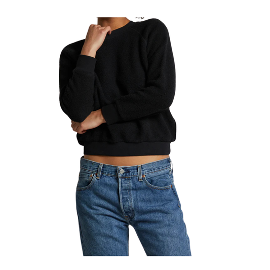 Person wearing a black sweater and blue jeans on a white background