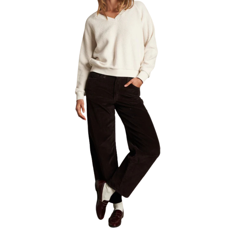 Person wearing a cream sweater and dark pants on a white background