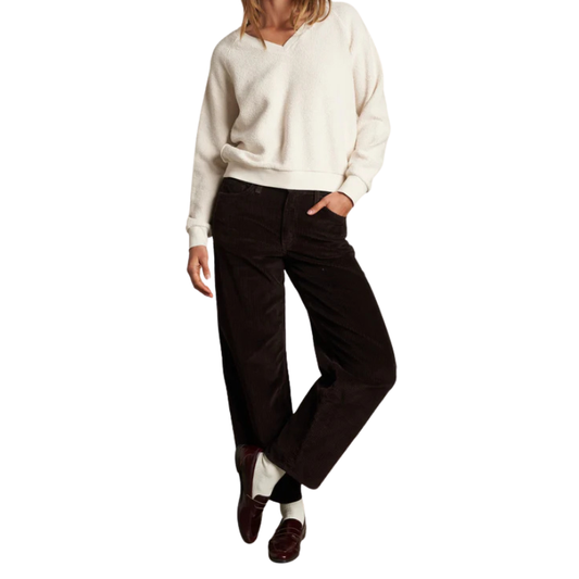 Person wearing a cream sweater and dark pants on a white background